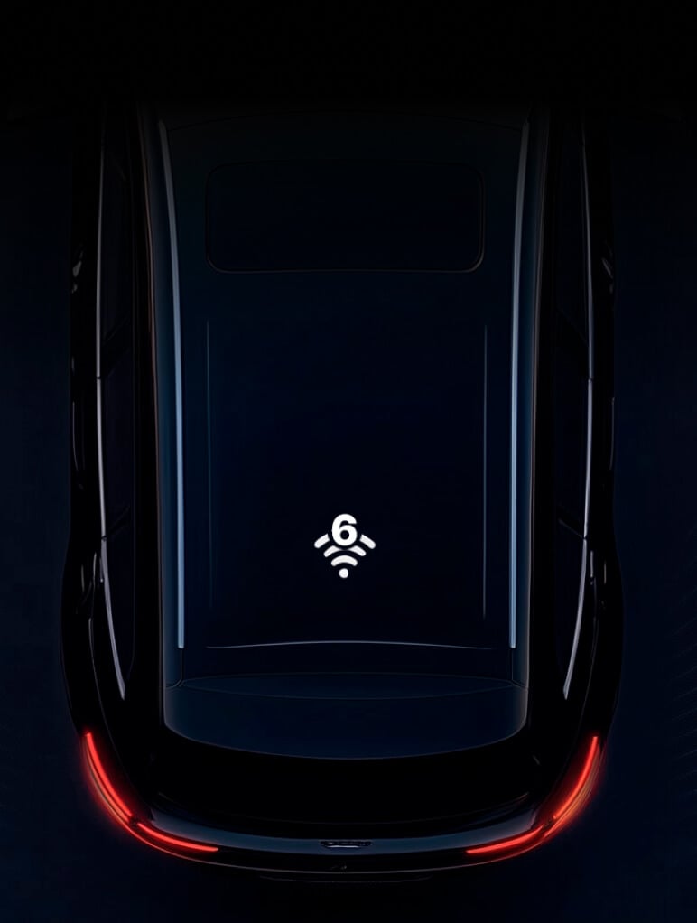 A darkly lit image of a car roof, showcasing a Wi-Fi 6 symbol in the center, suggesting connectivity. The car's rear lights create a red glow at the bottom, adding contrast to the sleek, reflective surface.