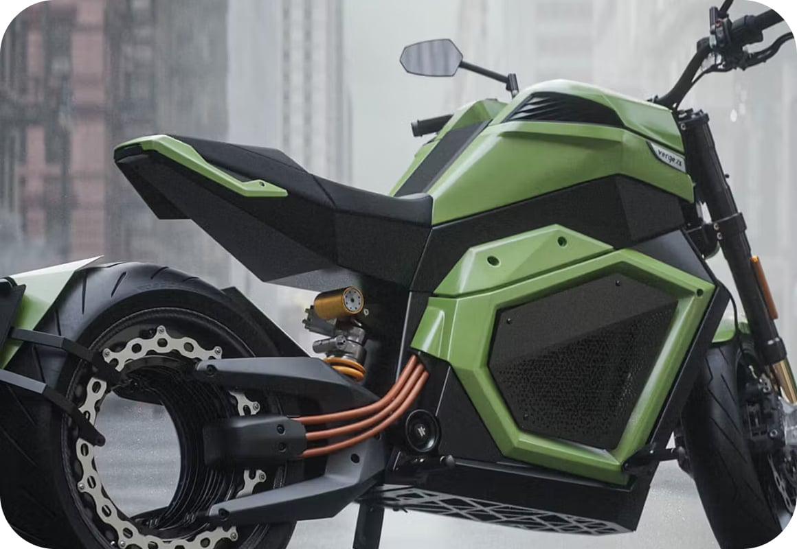 A futuristic green electric motorcycle with angular design, exposed wiring, and a large rear wheel, parked on a city street in rainy weather.