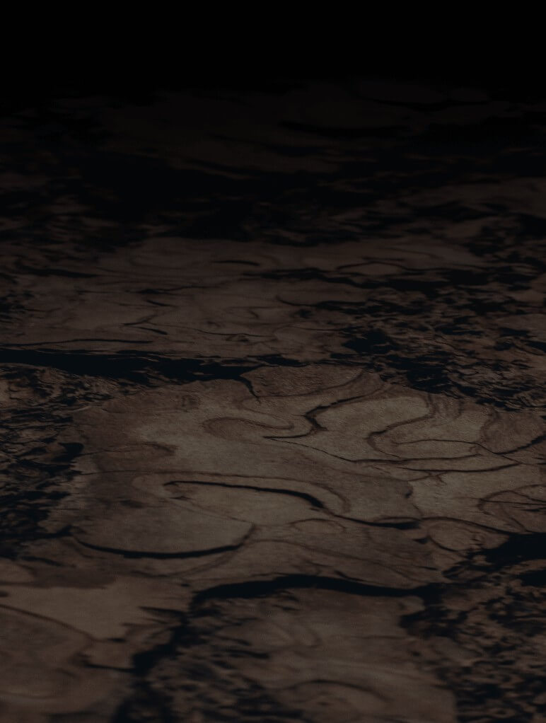Aerial view of a dark, textured surface resembling cracked, wavy patterns. The landscape is shadowy, suggesting a barren or dried terrain under low light conditions.